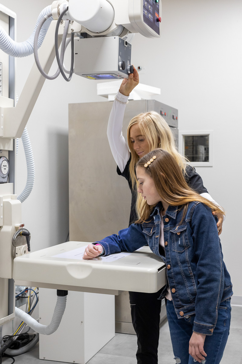 A medical provider reviews a patient's documents on a clipboard, pointing to a specific area to provide clarification or instructions.