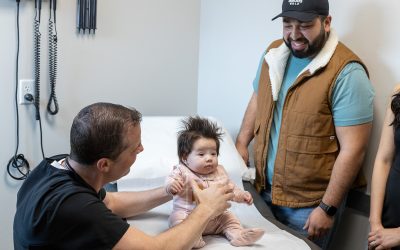 Pediatrician examining infant during check-up with parents in a medical office setting, emphasizing pediatric urgent care services at Ridgeline Medical.