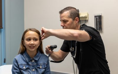 Pediatric urgent care visit with a healthcare professional examining a child's ear in a medical office setting.